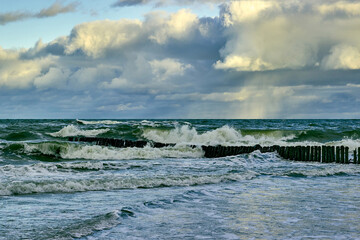 Stormy sea with low floating clouds illuminated by the dawn sun