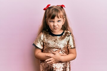 Little caucasian girl kid wearing festive sequins dress with hand on stomach because indigestion, painful illness feeling unwell. ache concept.