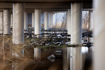 Many tall concrete columns reflected underneath an overpass water flow nature conservancy