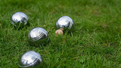 Close-up of steel petanque balls on a green lawn. Selective focus. Petanque balls made of...