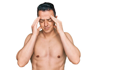 Handsome young man wearing swimwear shirtless with hand on head, headache because stress. suffering migraine.