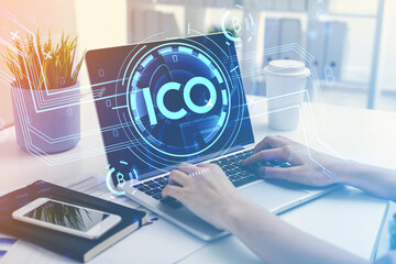 Businesswoman hands with laptop, ICO icon and office table