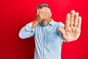 Middle age grey-haired man wearing casual clothes covering eyes with hands and doing stop gesture with sad and fear expression. embarrassed and negative concept.