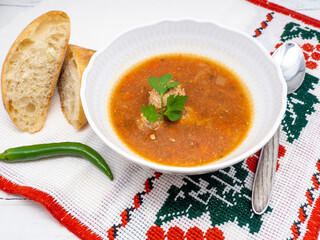 bowl with romanian meat balls soup served with hot pepper aside on traditional cloth
