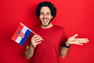 Handsome hispanic man holding croatia flag celebrating achievement with happy smile and winner...