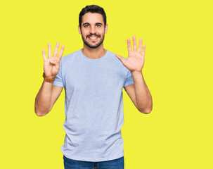 Young hispanic man wearing casual clothes showing and pointing up with fingers number nine while smiling confident and happy.