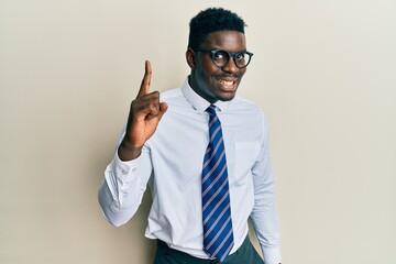 Handsome black man wearing glasses business shirt and tie pointing finger up with successful idea. exited and happy. number one.