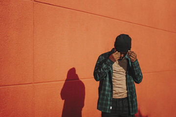 Handsome stylish Spanish man fixing his beanie on a red wall background