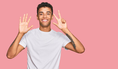 Young handsome african american man wearing casual white tshirt showing and pointing up with fingers number eight while smiling confident and happy.