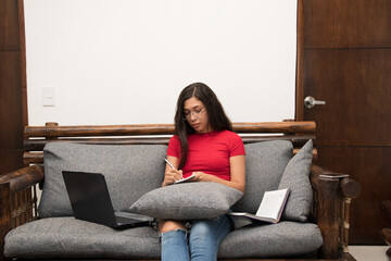 Obraz premium Colombian girl studies virtually and takes notes in a notebook