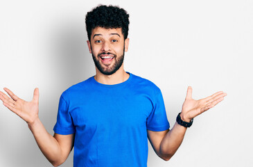 Young arab man with beard wearing casual blue t shirt celebrating crazy and amazed for success with arms raised and open eyes screaming excited. winner concept