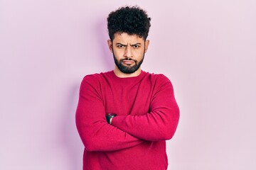 Young arab man with beard wearing casual pink sweater skeptic and nervous, disapproving expression on face with crossed arms. negative person.