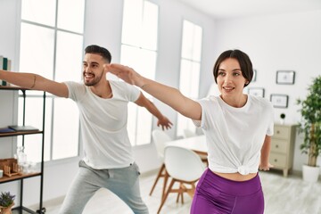 Obraz premium Young hispanic couple doing yoga at home