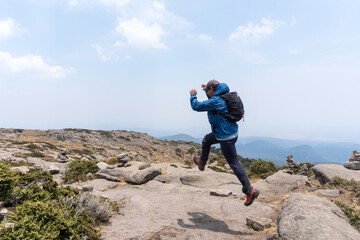 Hispanic hiker jumping up on mount Tlaloc under a cloudy sky in Mexico