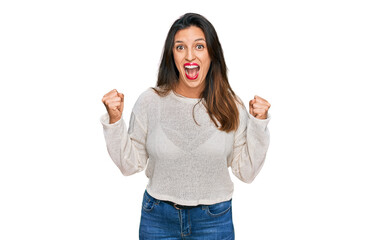 Beautiful hispanic woman wearing casual sweater celebrating surprised and amazed for success with arms raised and open eyes. winner concept.