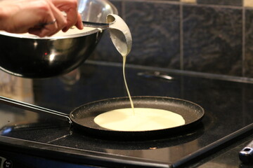 Homemade cooking, crepes making technique. Pouring batter into hot frying pan with ladle.