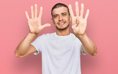 Hispanic young man wearing casual white t shirt showing and pointing up with fingers number nine...
