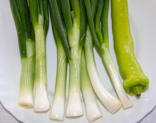 Green onions and a hot  pipper on a white plate