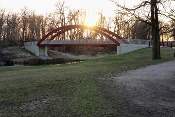 Pedestrian arch bridge over the river in the park at sunset