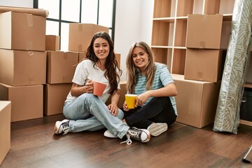 Young couple smiling happy drinking cup of coffee at new home.