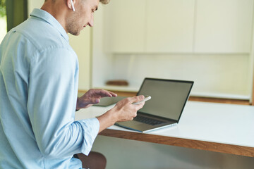 Cropped portrait of business man working from home with laptop and smartphone