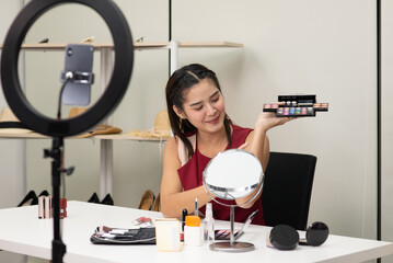 Beautiful Asian woman beauty makeup artist vlogger explain beauty cosmetic product on social media live streaming on smartphone. Online shopping business advertising by blogger or influencer concept.