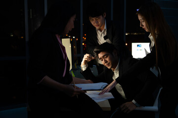 Busy Asian businessman and businesswoman office worker working overtime together at night. Business project colleague teamwork meeting brainstorming ideas for success business plan in office workplace