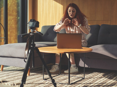 Successful business woman recording seminar with digital camera, tripod and laptop