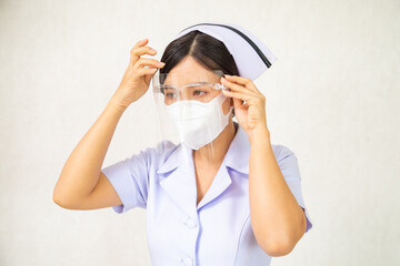 Asian female nurse in white uniform wearing surgical face mask and face shield protect covid-19 epidemic standing isolated white background. Female medical staff working in hospital health care center