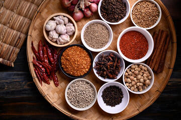 Various dry spices and herbs in a bowl on bamboo tray. Asian food ingredients (chili, clove,...