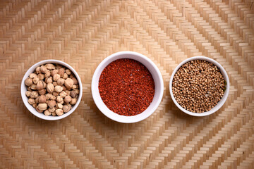 Chili powder, coriander seed and cardamom in a bowl on woven bamboo background, Asian food ingredients
