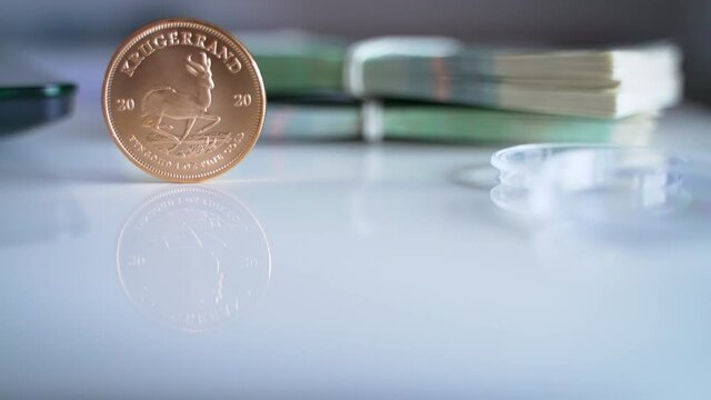 High-quality footage of the South African Krugerrand Coin in a vertical position and the Official currency of Poland in the background. Two sets of Polish zloty and Krugerrand. Narodowy Bank Polski. 