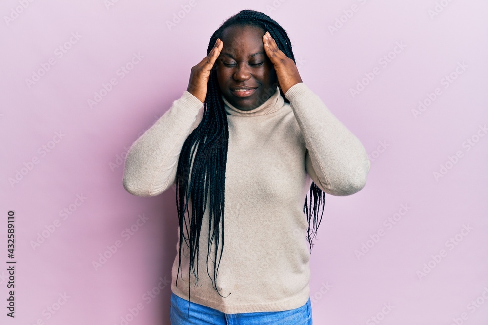 Wall mural Young black woman with braids wearing casual winter sweater with hand on head for pain in head because stress. suffering migraine.