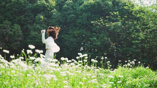 4kk slow motion of young girl enjoy the nature relax freedom concept Young beautiful Asian girl happily Dancing in circles in the grass in the forest full of flowers