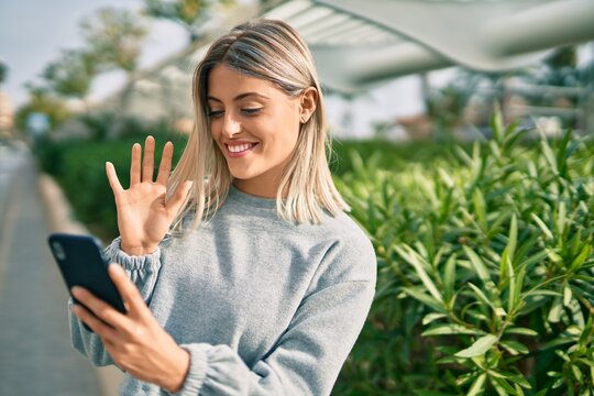 Young blonde girl smiling happy doing video call using smartphone at the city