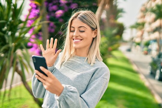 Young blonde girl smiling happy doing video call using smartphone at the park.