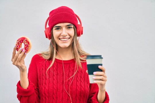 Young hispanic woman having breakfast using headphones at the city.