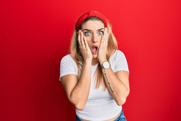 Young caucasian woman wearing casual white t shirt afraid and shocked, surprise and amazed expression with hands on face