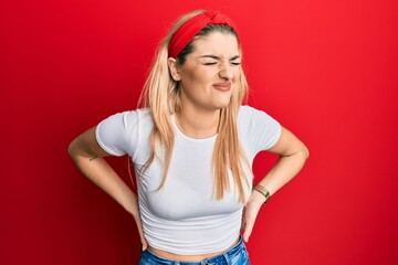 Young caucasian woman wearing casual white t shirt suffering of backache, touching back with hand, muscular pain