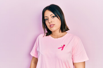 Young hispanic woman wearing pink cancer ribbon on t shirt looking sleepy and tired, exhausted for fatigue and hangover, lazy eyes in the morning.