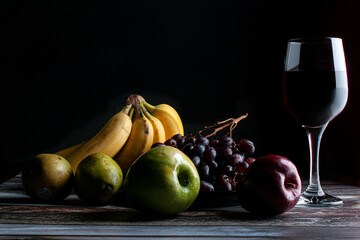 Baroque, renaissance still life fruits on a wooden rustic table with a glass of wine on the side...