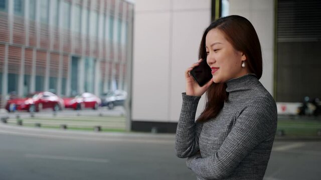 4k slow motion side view of Asian businesswoman making a phone call and walking on the city street