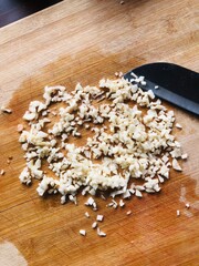 Sliced garlic cloves on wooden chopping Board