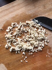 Sliced garlic cloves on wooden chopping Board