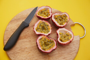 Top view of chopped purple passion fruit and a knife on a wooden board
