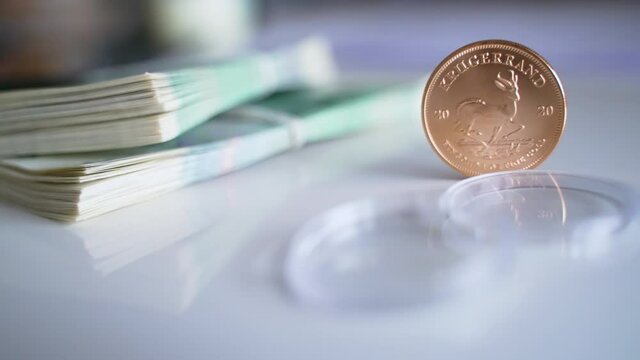 High-quality footage of the South African Krugerrand Coin in a vertical position with the Official currency of Poland in the background. Sets of zlotych and Krugerrand. Narodowy Bank Polski. Bank Of