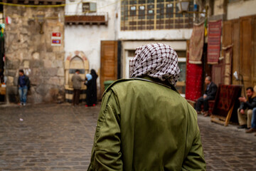 Street view, downtown Damascus, Syria featuring a man from behind wearing a Palestinian style...