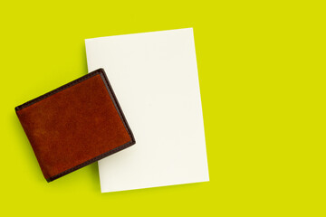 Brown wallet with white paper on green background.