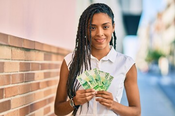 Young african american woman smiling happy holding norwegian 50 krona banknotes at the city.