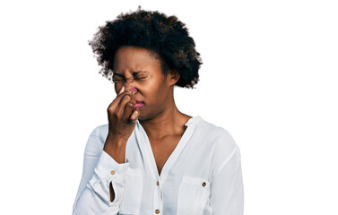 Fototapeta na wymiar African american woman with afro hair wearing casual white t shirt smelling something stinky and disgusting, intolerable smell, holding breath with fingers on nose. bad smell